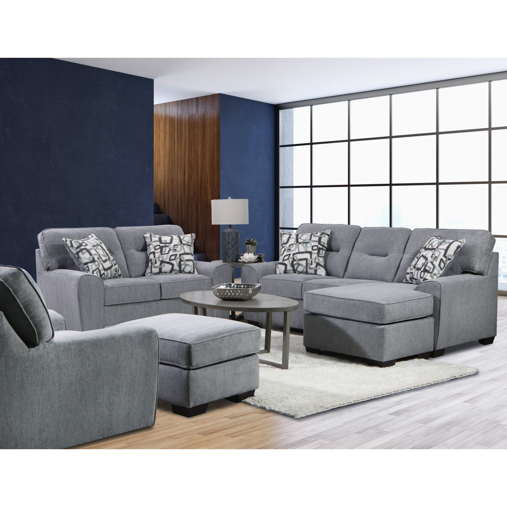 Full view of the contemporary dark gray fabric sofa and loveseat set, complete with an armchair and ottoman, in a bright, modern living space.