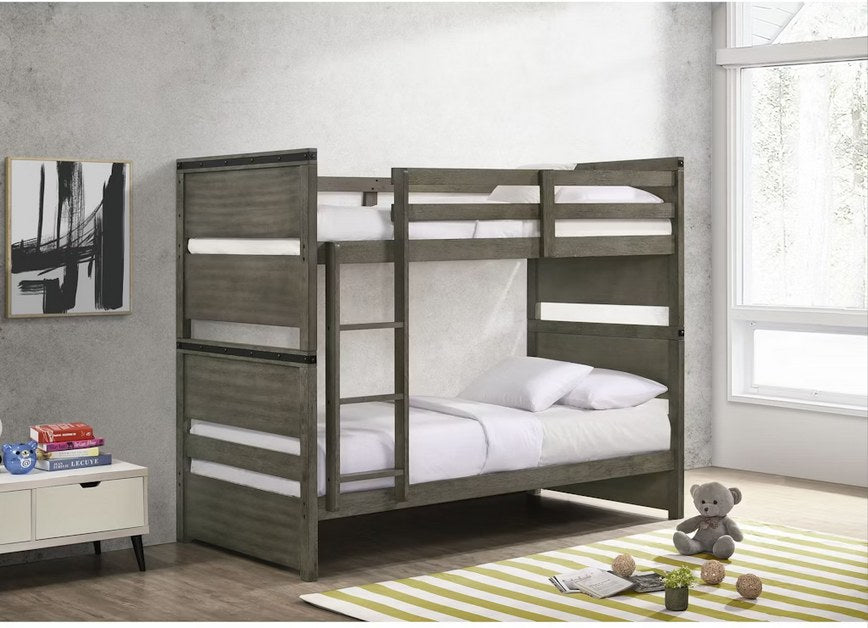 Full front view of the Elements International Twin Over Twin Bunk Bed, showcasing its rustic gray finish, ladder, and overall modern industrial design in a styled room.