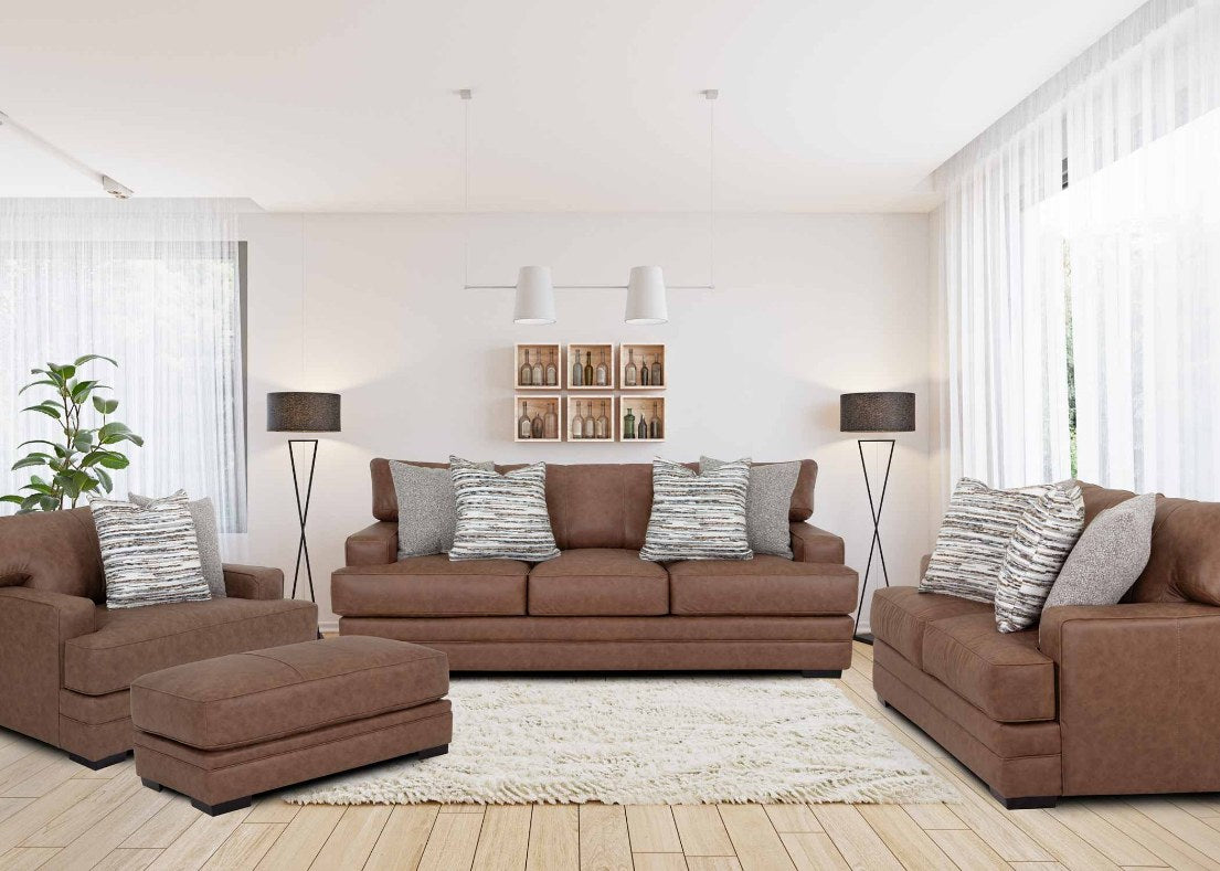 Full living room set (sofa, loveseat, chair, and ottoman) featuring a rich, warm brown leather-look upholstery, plush cushions, wide padded arms, and two striped throw pillows, set in a bright, inviting room.