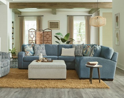 Alternative full view of the L-shape sectional in a vibrant blue, highlighting its relaxed style and decorative accent pillows within a coordinating room setting.