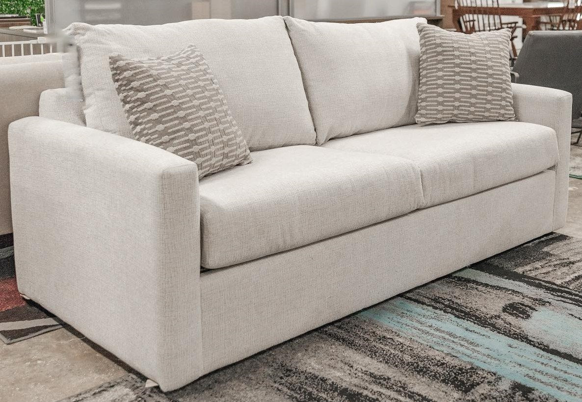 Full, inviting view of the modern light gray sofa, showcasing its clean lines and two decorative throw pillows.
