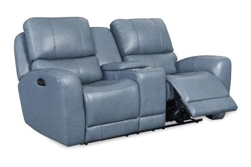 Front-angled view of a two-seater power reclining loveseat with a center console, upholstered in a dusty blue leather, with recliners partially extended and power controls visible.