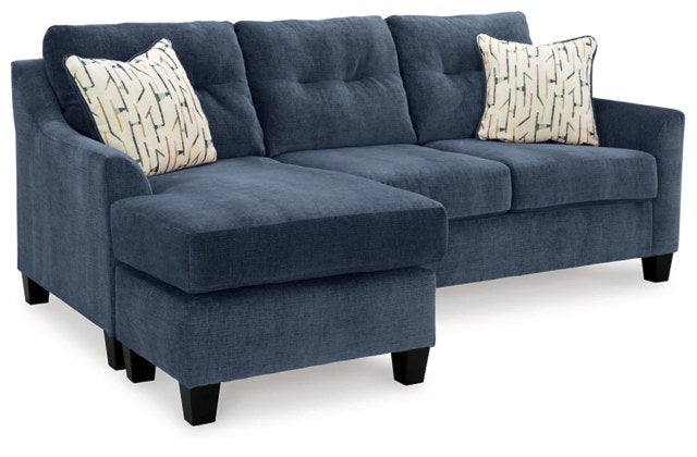 Ashley Amity Bay Tufted Fabric Club Chair, Blue and Brown - Full front view of the Ashley sectional sofa with a left-arm facing chaise, upholstered in a rich blue textured fabric, showcasing tufted back cushions and two patterned accent pillows.